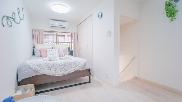 A bedroom with a bed, bedside table, and a window with curtains. - NICE HOUSE (Osaka)