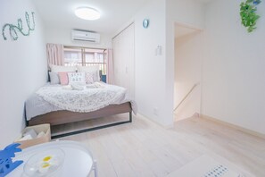A bedroom with a bed, bedside table, and a window with curtains. - NICE HOUSE (Osaka)