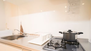 A kitchen with a stove, sink, and white cabinets. - Doraemon's House (Osaka)