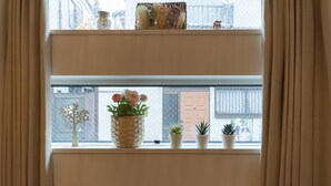 A window with a view of a building, a decorative tree, and three potted plants. - MARE HOUSE-1F (Tokyo)