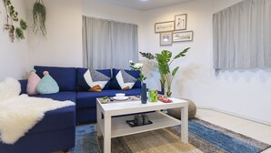 Un salon moderne avec un canapé bleu, une table basse blanche et des plantes décoratives.