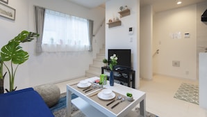Un salon moderne avec une table à manger pour deux personnes, un téléviseur et un escalier menant à un autre niveau.
