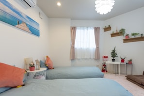 Ein Schlafzimmer mit zwei Betten, einem Bild an der Wand, einem kleinen Tisch mit Pflanzen und einem Feuerlöscher.