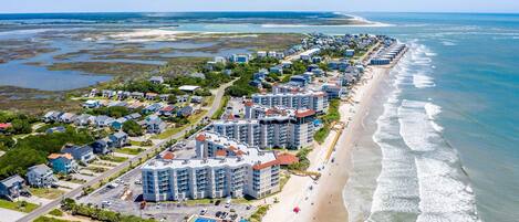 Un hotel costero con varias edificaciones, una playa y vista al océano.