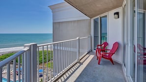 A balcony with a view of the ocean, a pool area, and red chairs. - Top Floor Unit with amazing Views (North Topsail Beach)