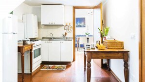 Cozinha com armários brancos, fogão e área de jantar com mesa e cadeiras.