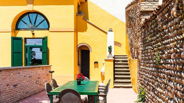 Um pátio com mesa e cadeiras, um muro de tijolos e um edifício amarelo com janela e porta.