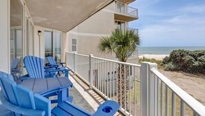 Ein Balkon mit blauen Stühlen und einem Tisch mit Blick auf einen Strand.