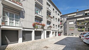 A modern building with multiple balconies, some with flower boxes, and a paved driveway with parked cars. - Breath of Lake Garda Apartment (Riva del Garda)