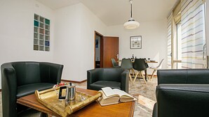 A modern living room with leather sofas, a wooden coffee table, and a dining area in the background. - Breath of Lake Garda Apartment (Riva del Garda)