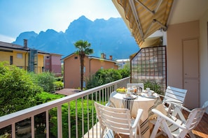 Un balcon avec une table dressée pour deux personnes, offrant une vue sur un paysage montagneux.