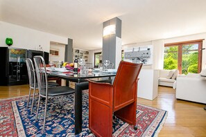 A modern dining area with a glass table, metal chairs, and a patterned rug.