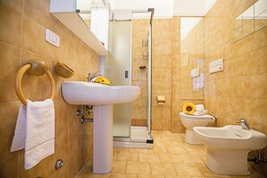 Ein Badezimmer mit Waschbecken, Bidet, Toilette und Dusche.