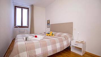 Un dormitorio ordenado con cama, mesita de noche y ventana.