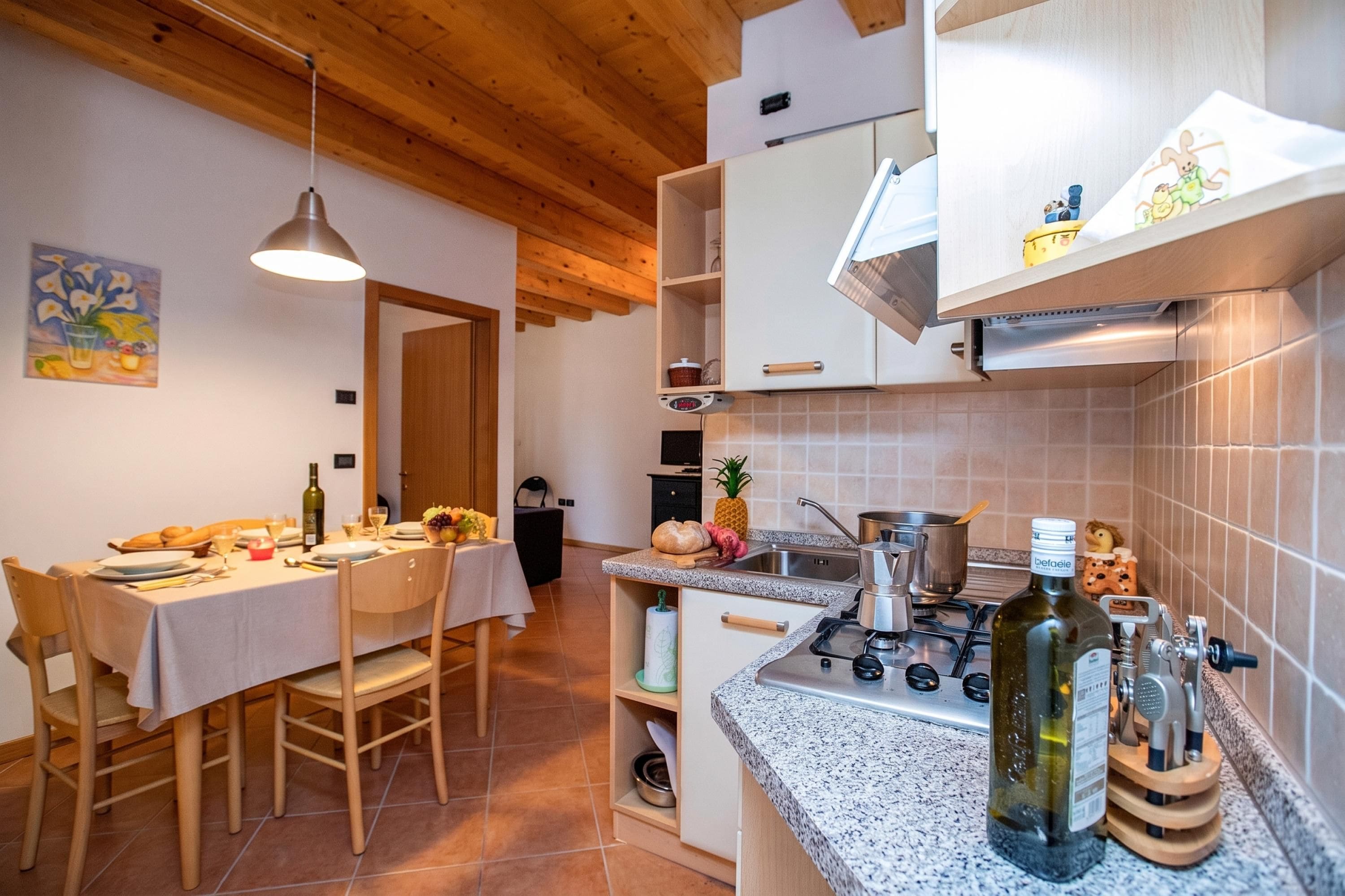 Una cocina moderna con estufa a gas, un lavamanos y un comedor con una mesa preparada para dos.