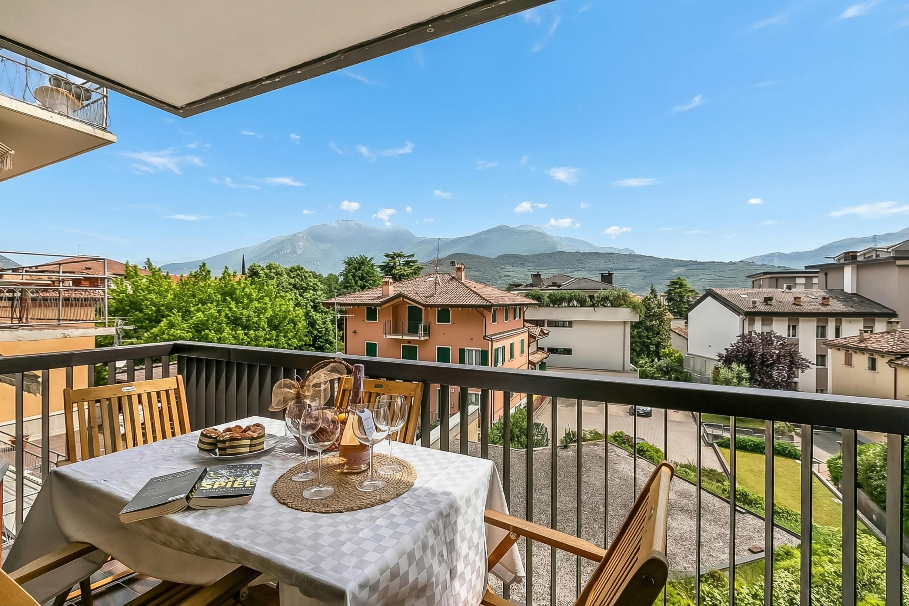 Un balcón con una mesa lista para comer, con vista a una zona residencial y montañas.