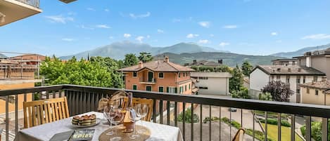 Un balcón con una mesa lista para comer, con vista a una zona residencial y montañas.