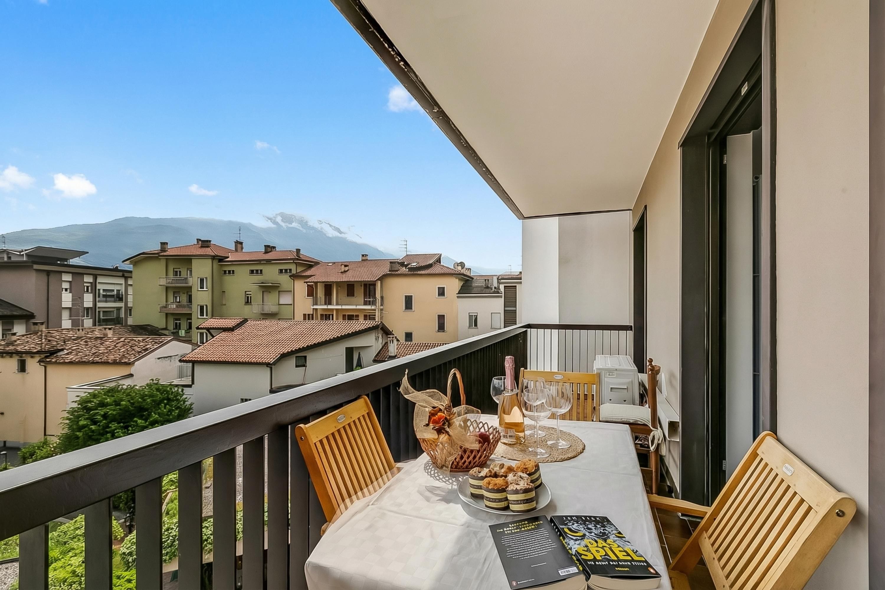 Un balcon avec une table dressée pour deux personnes, un panier, une bouteille et un livre.