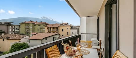 Un balcon avec une table dressée pour deux personnes, un panier, une bouteille et un livre.