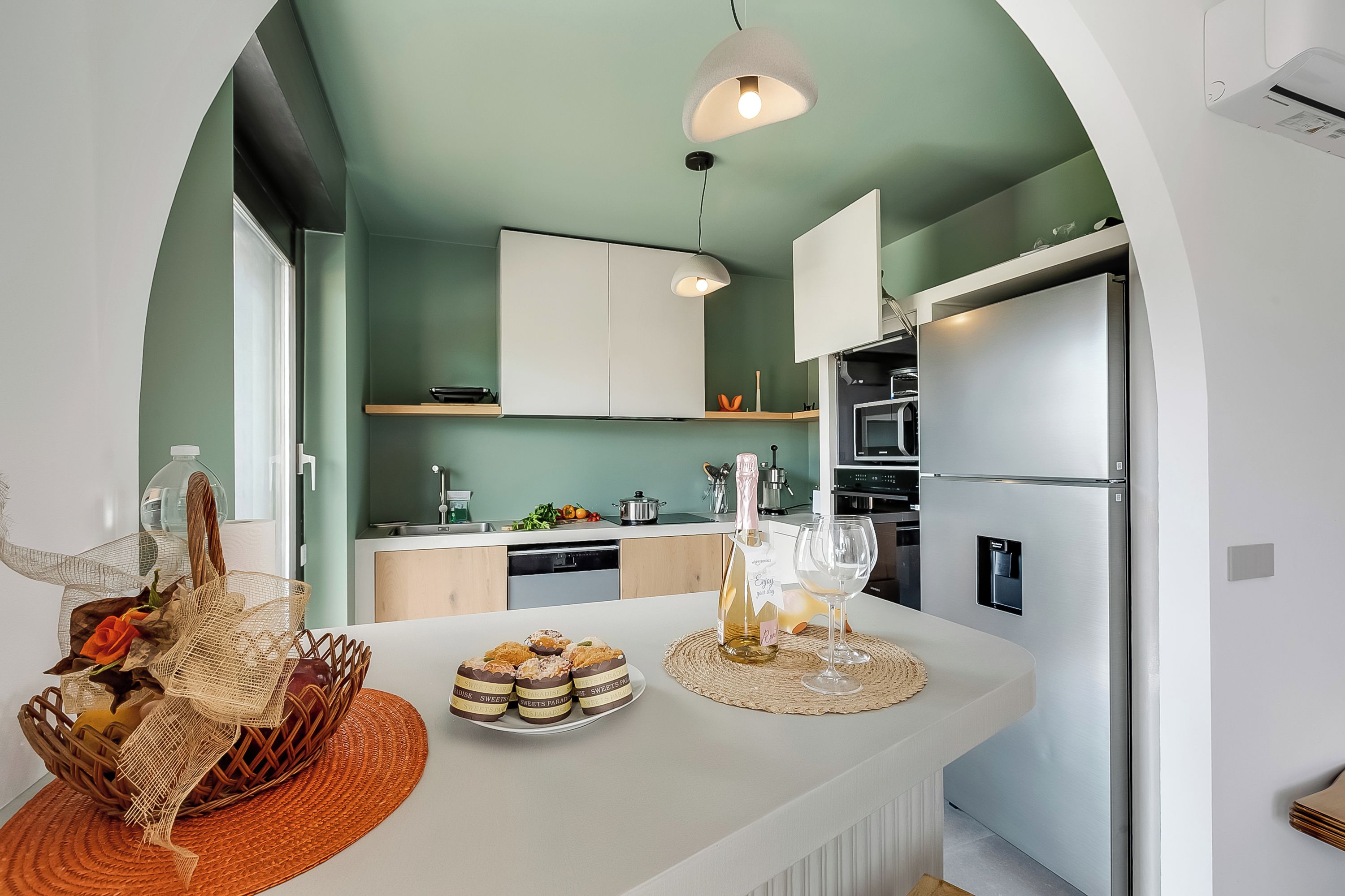 Una cocina moderna con una isla central, armarios blancos y una pared de acento verde.