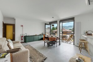 A modern living room with a sofa, a dining table, and a view of the outdoors. - Appartamento Amy (Riva del Garda)