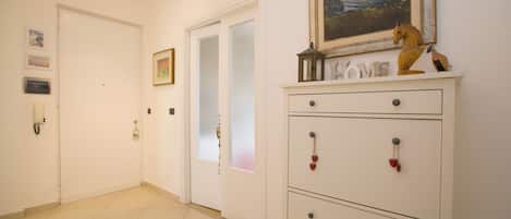 A hallway with a white door, a white cabinet with drawers, a framed painting, and a small horse figurine.