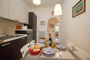 A dining area with a table set for four, a kitchen with modern appliances, and a view into another room.