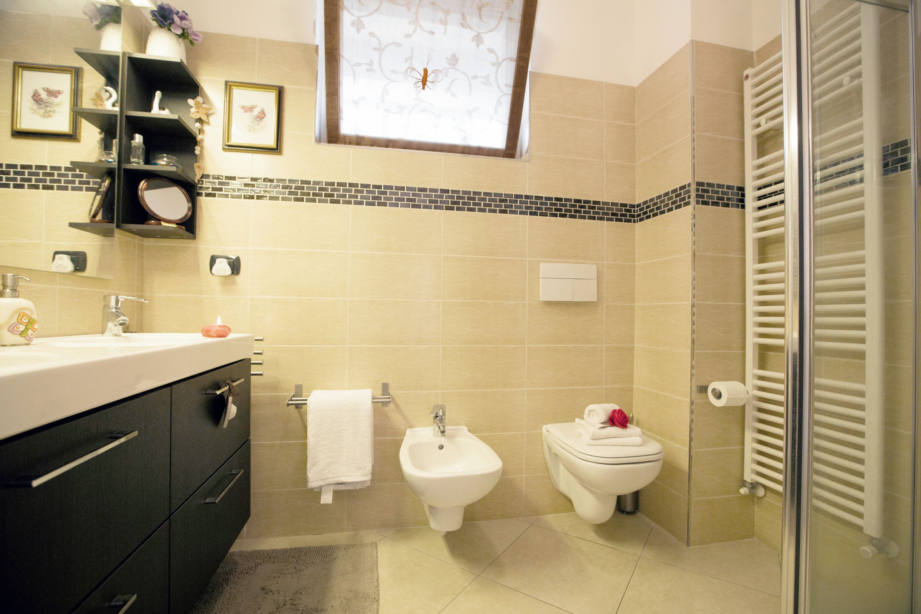 Ein Badezimmer mit Bidet, Toilette, Waschtisch mit Spiegel und Handtuchhalter.