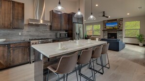 A modern kitchen with a large island, stainless steel appliances, and pendant lighting. - AC, Large Upright Arcade, Dreamy Kitchen, Designer Furnished, Grill, Fast Wifi, Spa – The Glenmore (South Lake Tahoe)