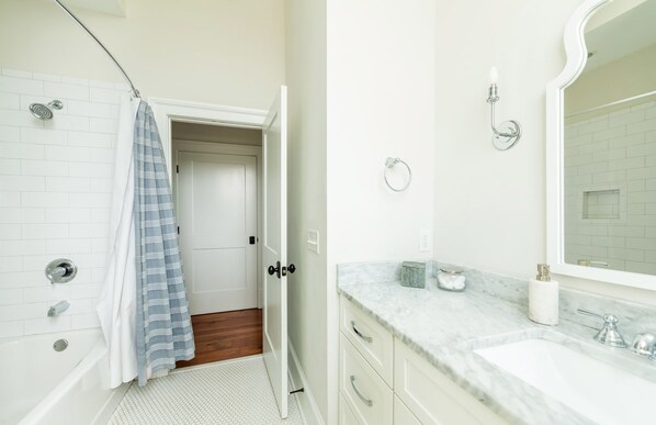A bathroom with a shower, a bathtub, a vanity with a mirror, and a towel rack. - Downtown Chic w/ Private Parking 1 Block From Broughton St. by Lucky Savannah (Savannah)