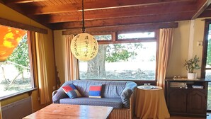 Ein gemütliches Zimmer mit einer Couch, einem Holztisch und Blick ins Freie.