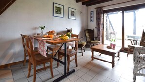 Un comedor con una mesa y sillas de madera, una planta en maceta y vistas al exterior.