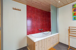 A bathroom with a wooden bathtub, red tiled walls, and a wooden towel rack. - La Roche Cozy Forest Escape (Rendeux)
