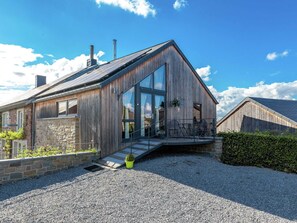 Een modern houten huis met een schuin dak, grote ramen en een stenen fundering.