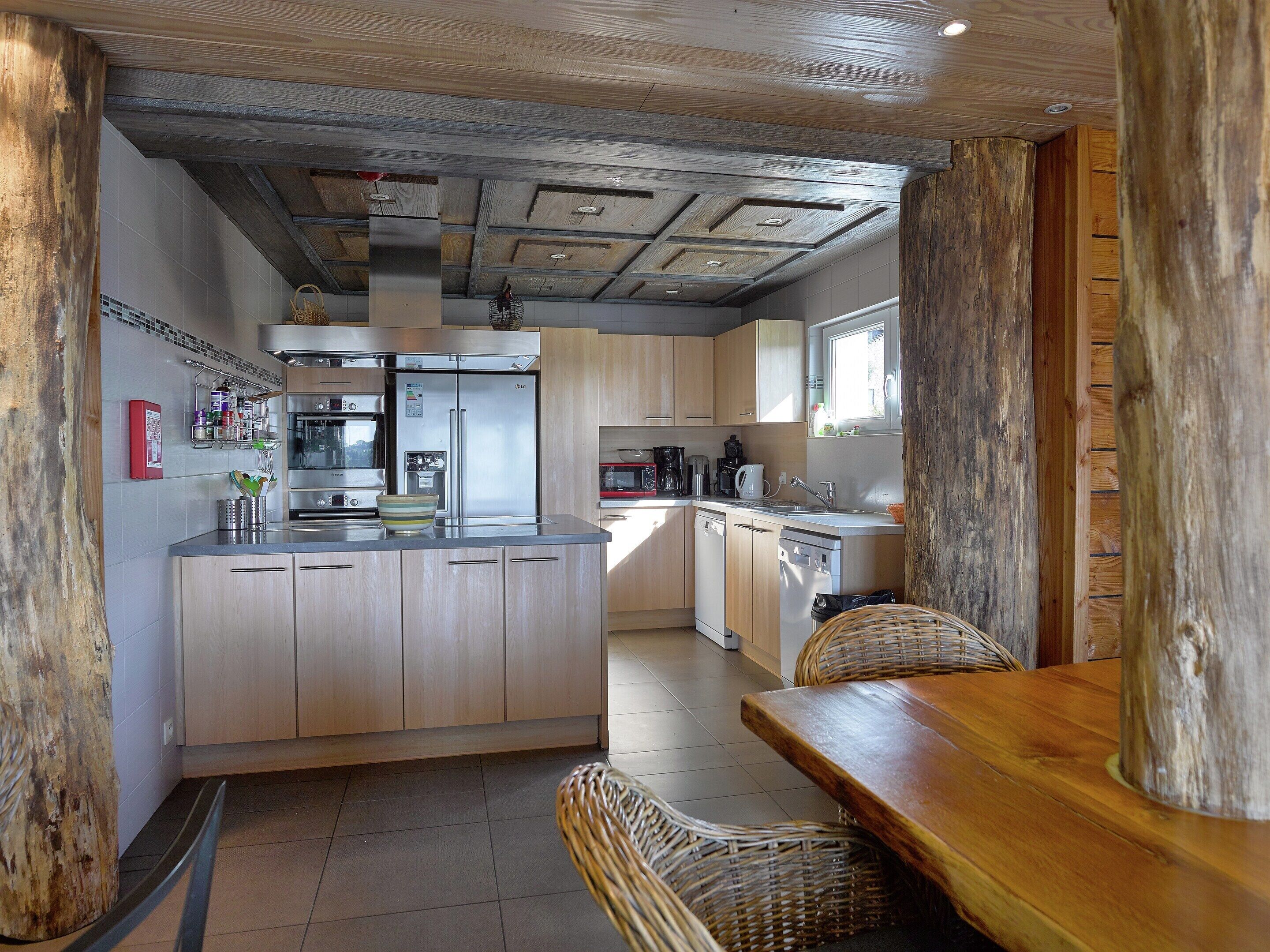 Eine moderne Küche mit Holzausstattung, Edelstahlgeräten und einer zentralen Kochinsel.