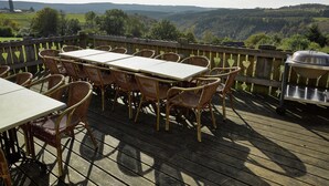 Eine Holzterrasse mit Tisch und Korbstühlen, mit Blick auf eine malerische Landschaft.