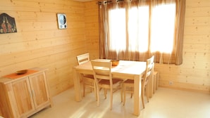 Ein Esszimmer mit Holztisch und -stühlen, einer kleinen Kommode und einer Wanduhr.