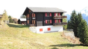 Eine zweistöckige Chalet mit Balkon, vor einer Bergkulisse gelegen.