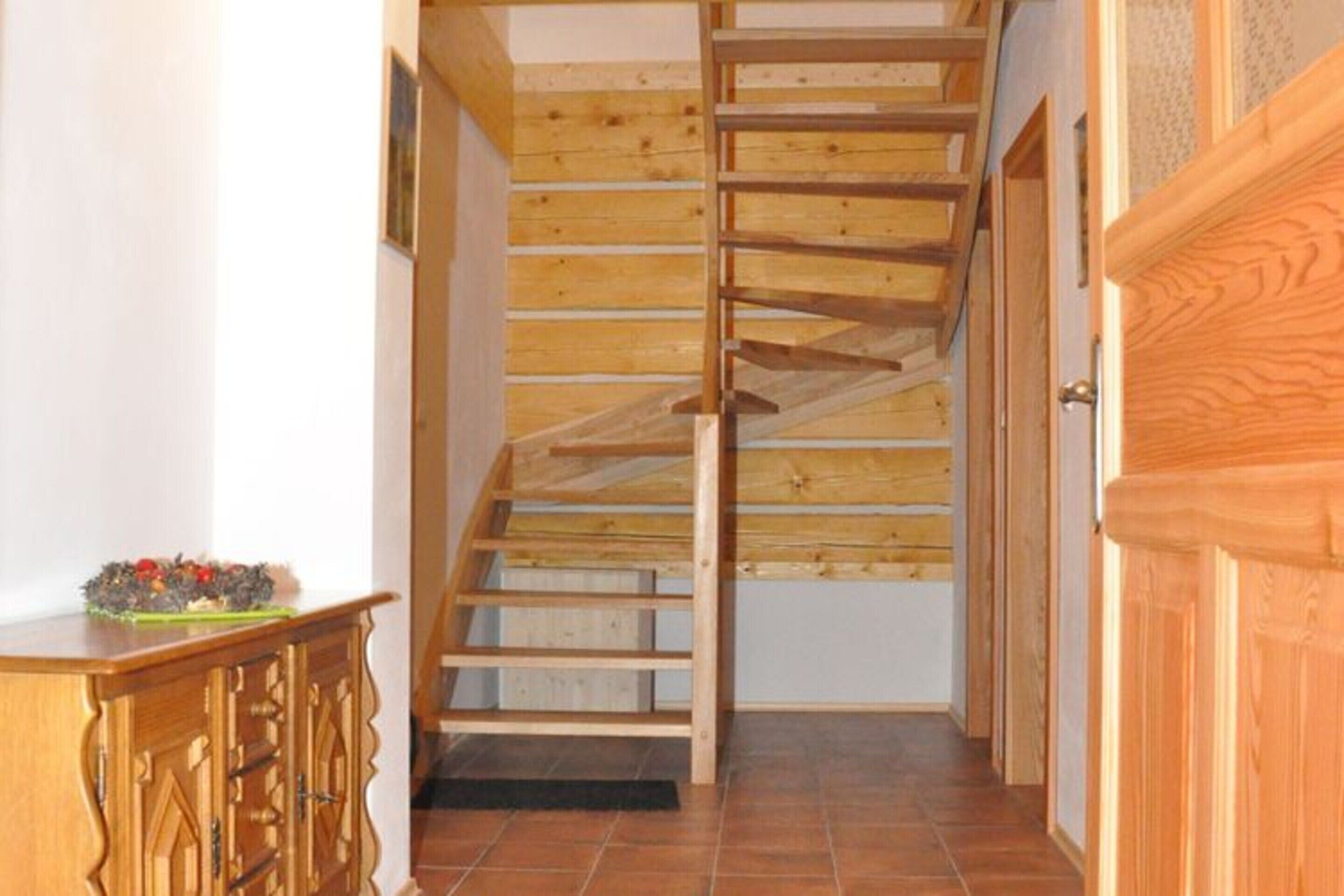 Una escalera de madera con barandilla que lleva a un piso superior.