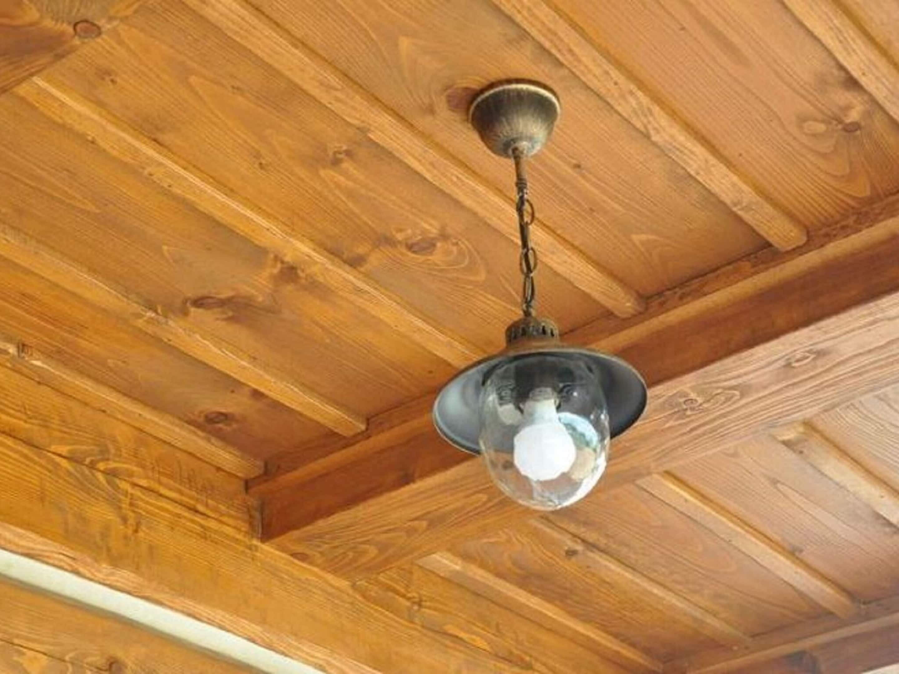 A wooden ceiling with a hanging light fixture.