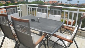 A balcony with a table and chairs, overlooking a coastal area with boats and buildings. - Apartment in Dubrovni With Garden (Dubrovnik)