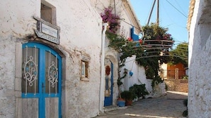A narrow stone-paved street flanked by white buildings with blue doors and windows. - Villa in Corfu Near Porto Timoni Beach (Corfu)
