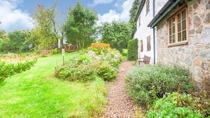 A stone building with a garden path leading to a bench.
