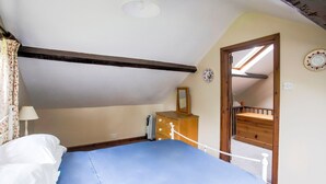 A bedroom with a bed, dresser, and a skylight.