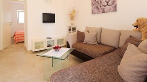 Un salon avec un canapé, une table basse en verre, un téléviseur, un tableau et un chien.