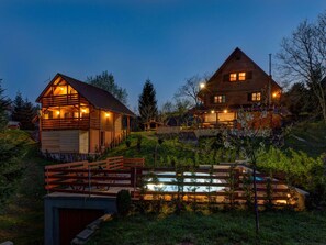 A two-story wooden cabin with a visible deck and a swimming pool in the foreground. - Tranquil Holiday Home in Kvarner with Hot Tub (Brod Moravice)