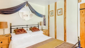 Une chambre à coucher avec un lit, des tables de chevet, un miroir et une armoire en bois.