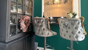 Un coin repas avec un buffet en bois foncé, deux fauteuils capitonnés agrémentés d’éléments décoratifs et un mur vert.