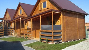 A row of wooden cabins with pitched roofs and a covered porch area. - Bungalow in Miedzyzdroje Near the Beach (Międzyzdroje)