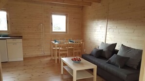 A cozy wooden cabin with a dining area, a sofa, and a small kitchen. - Bungalow in Miedzyzdroje Near the Beach (Międzyzdroje)
